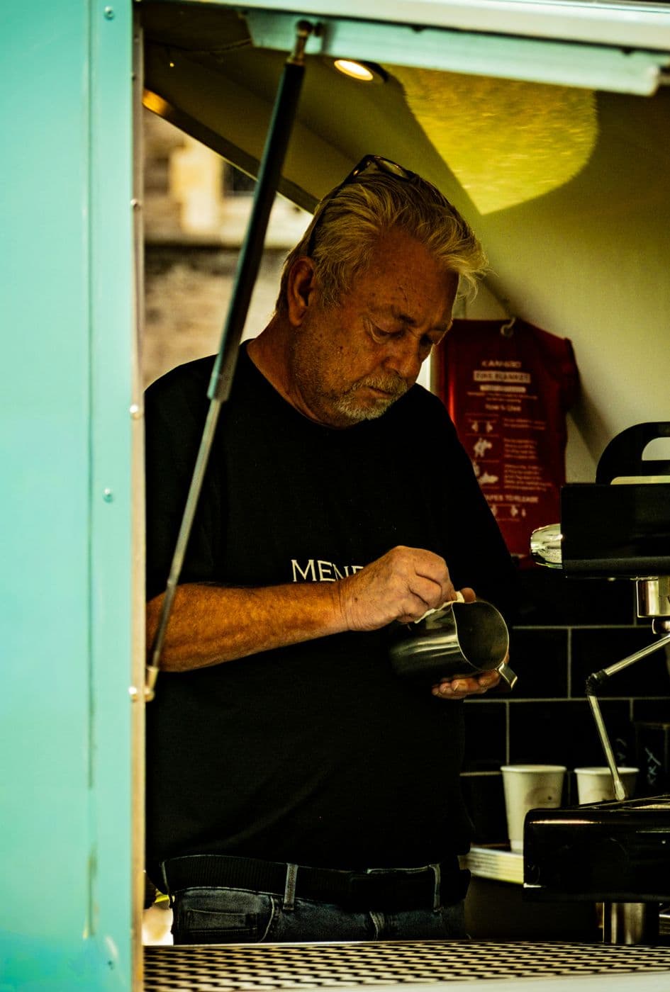 Barista qui prépare un café au lait dans un camion à café turquoise