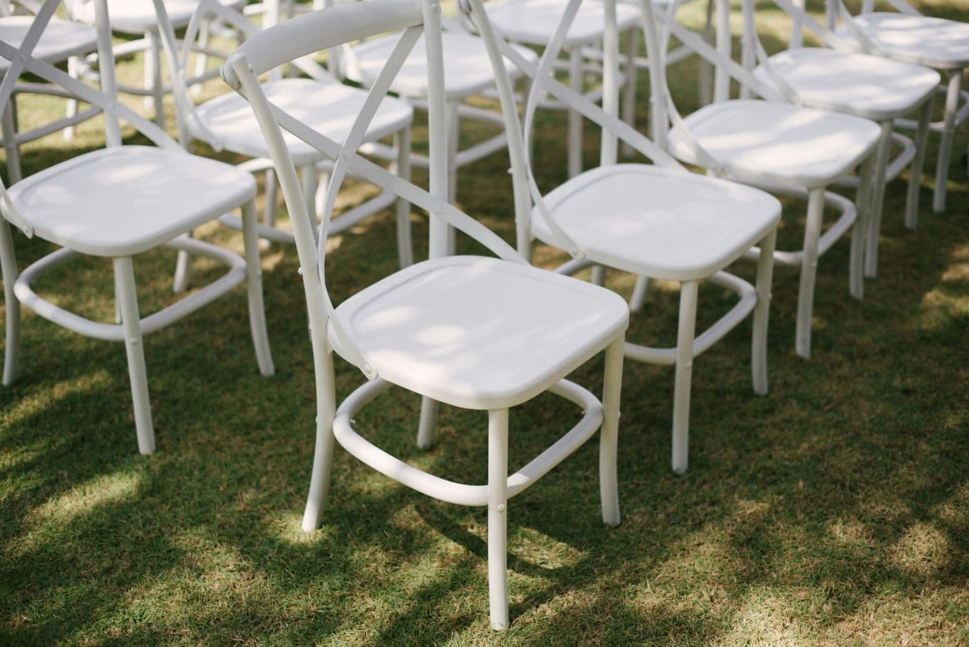 Rows of white wooden chairs set out on the lawn for a ceremony