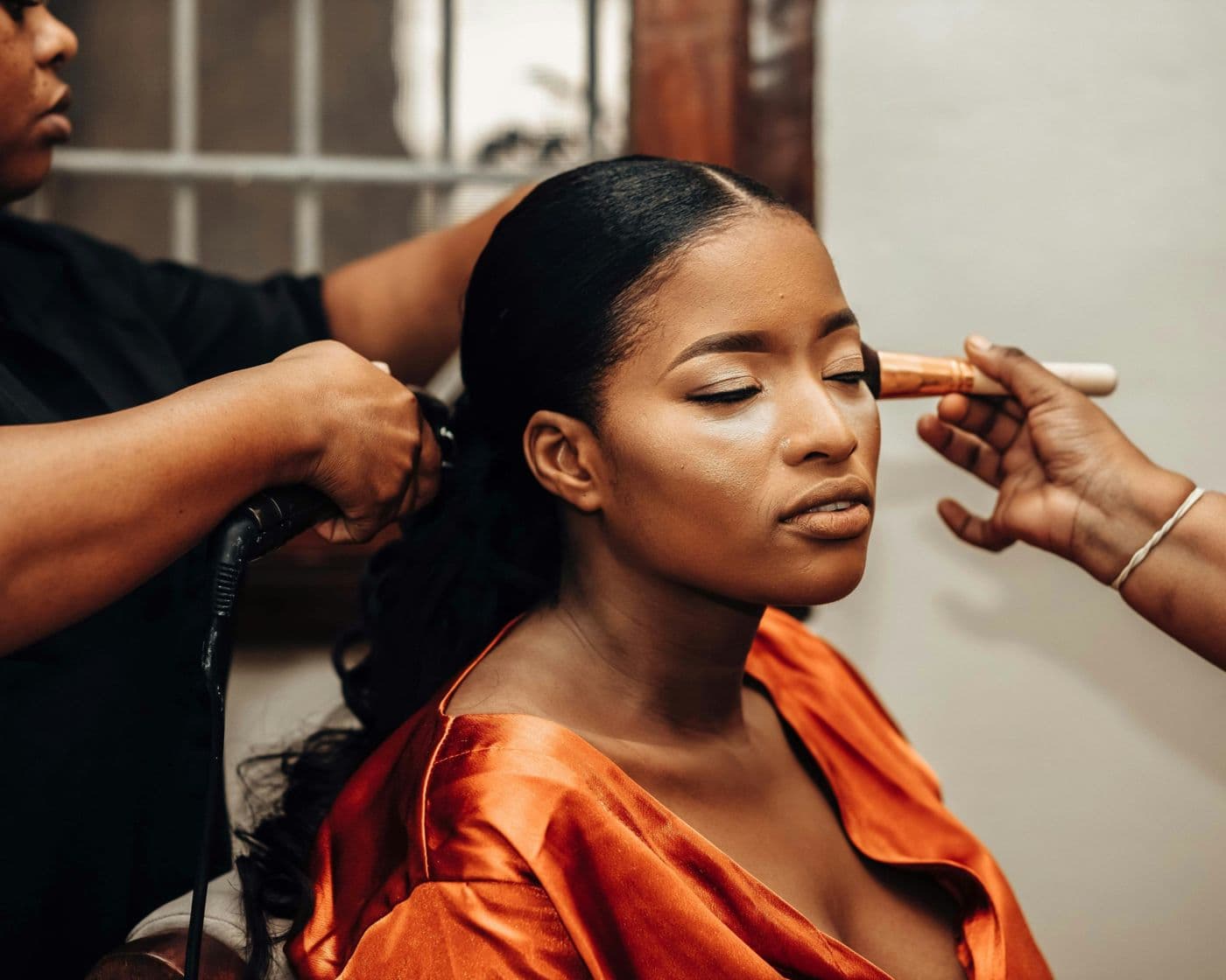 Bride in an orange robe having her hair and make-up done before the ceremony