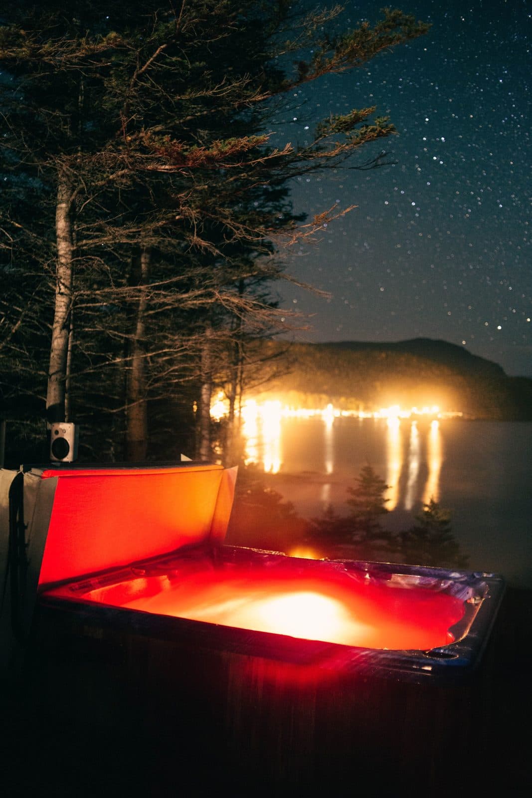 Jacuzzi éclairé de nuit au bord d'un lac sous les étoiles