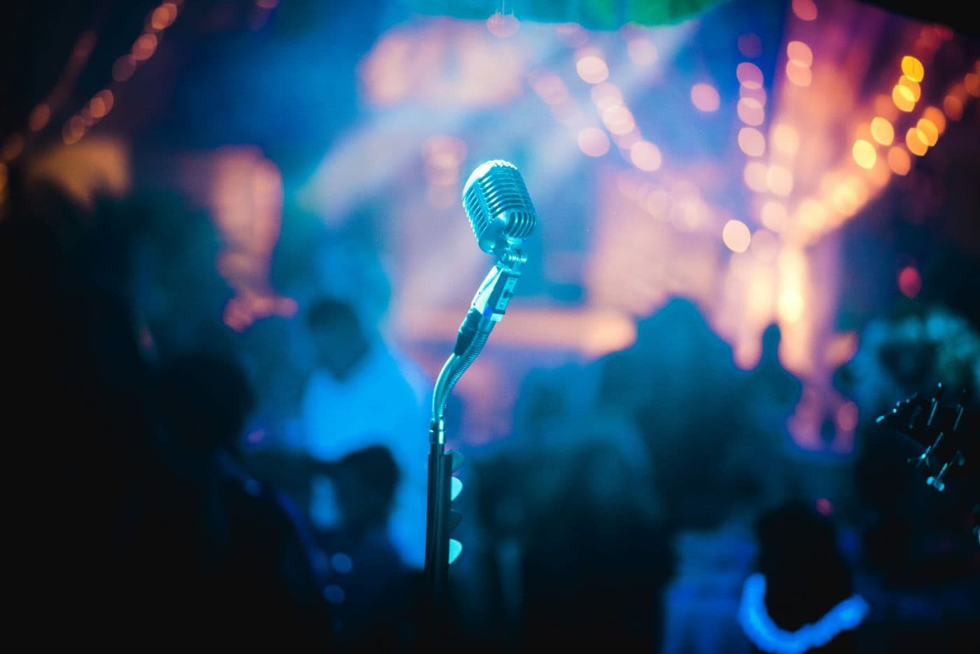 Vintage microphone on a stand in front of a lit-up concert crowd