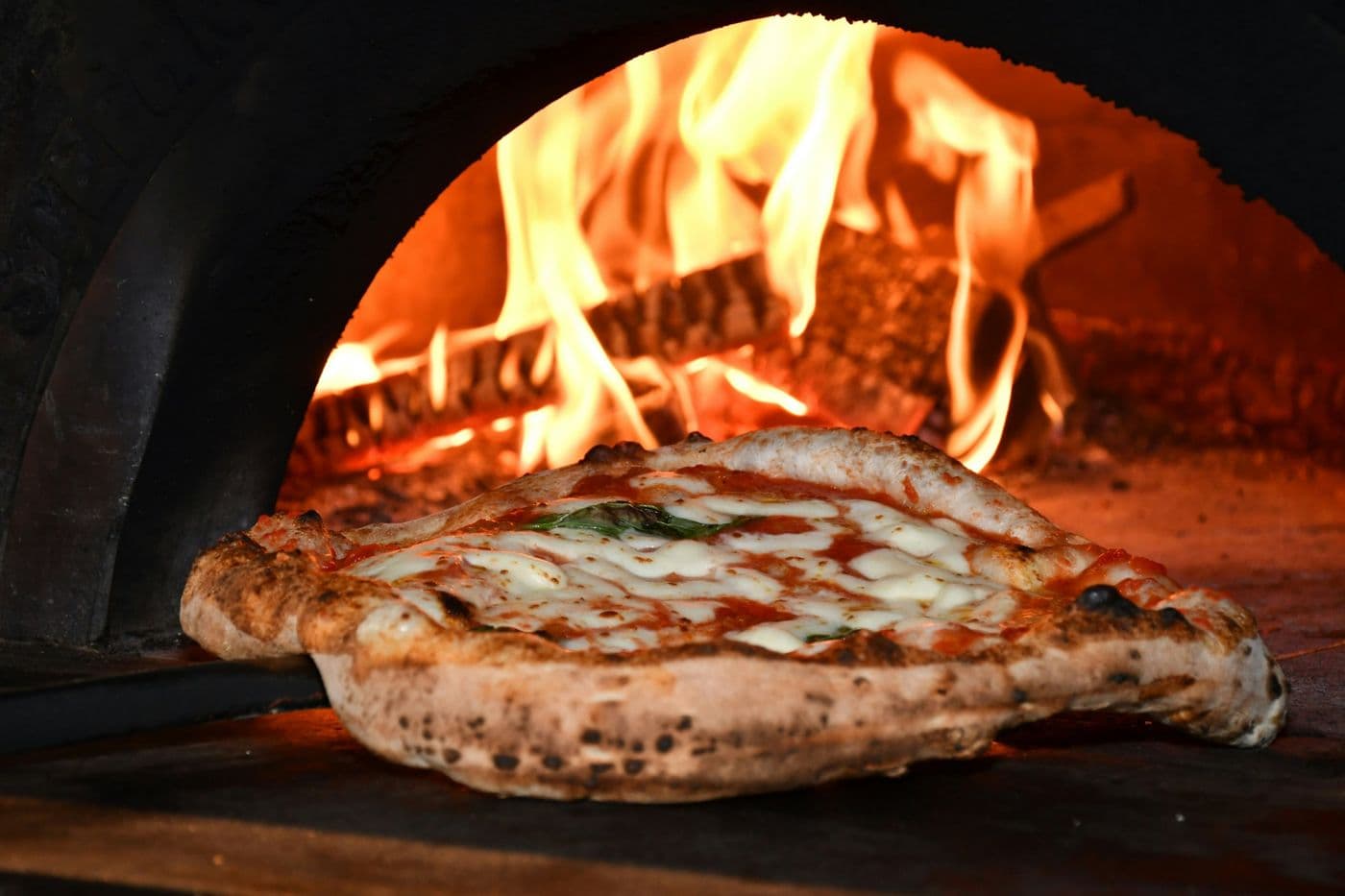 Margherita pizza coming out of a wood-fired oven