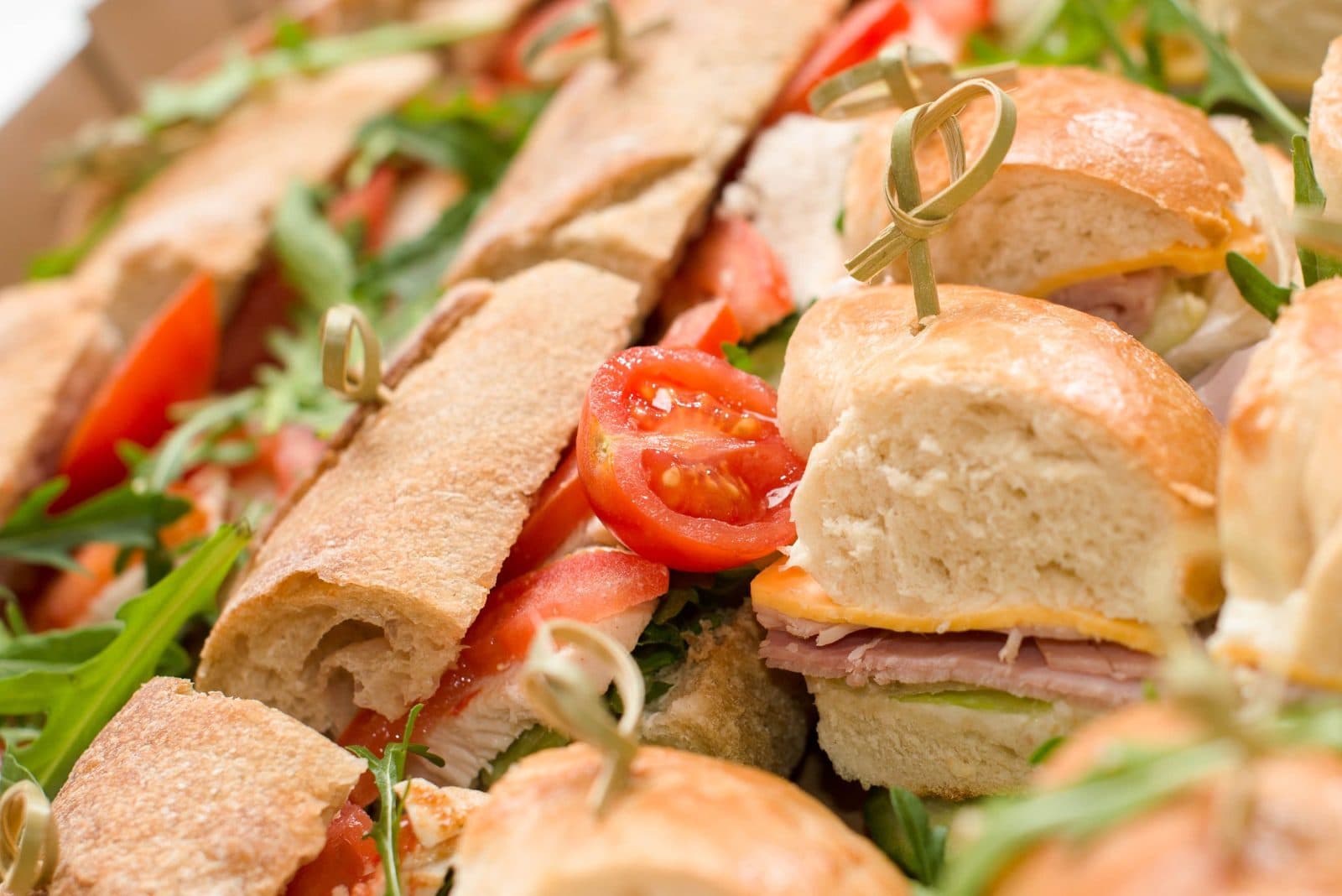 Platter of mini sandwiches with ham, cheese and tomato