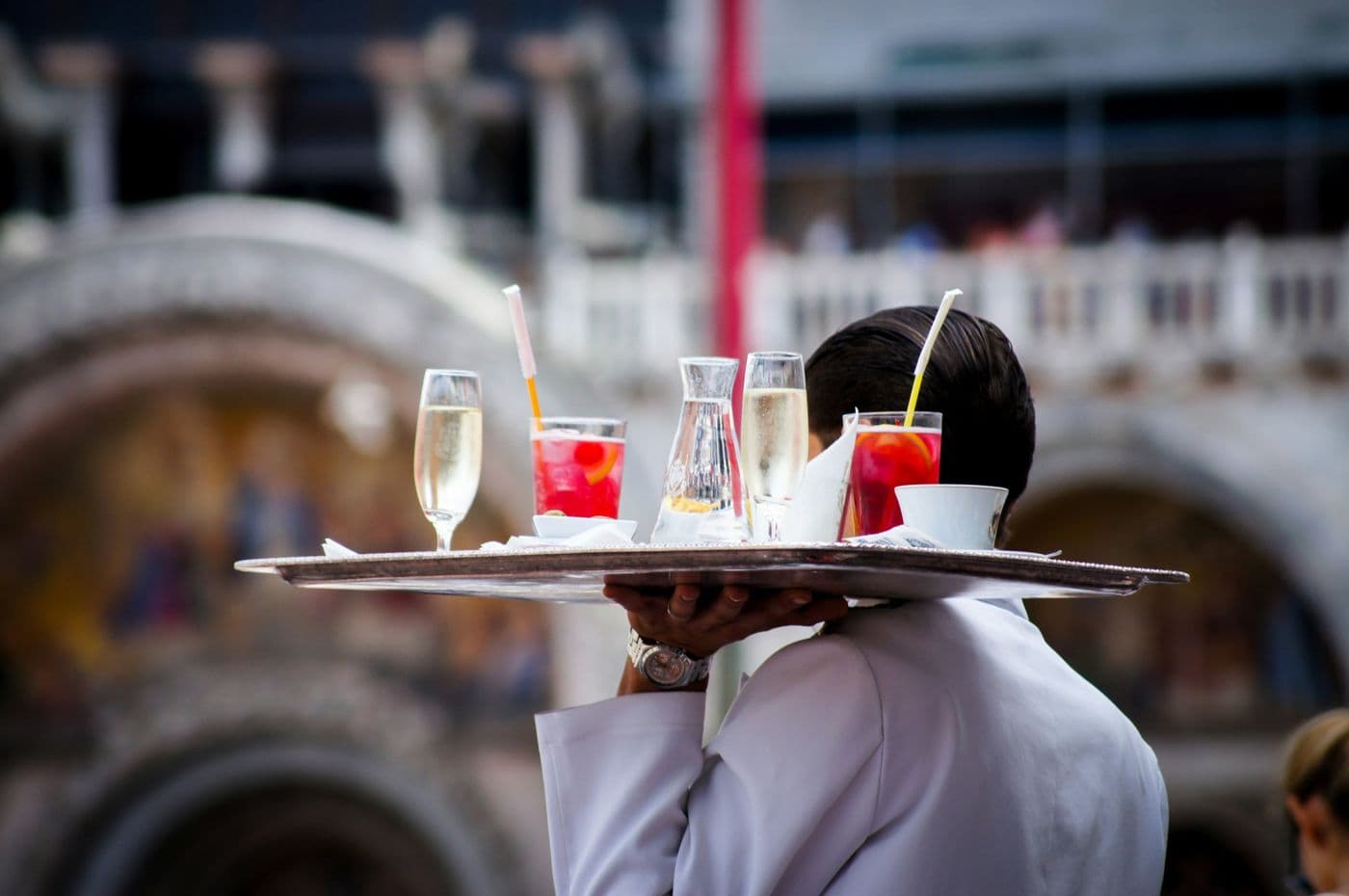Waiter in a white jacket carrying a tray of champagne and cocktails
