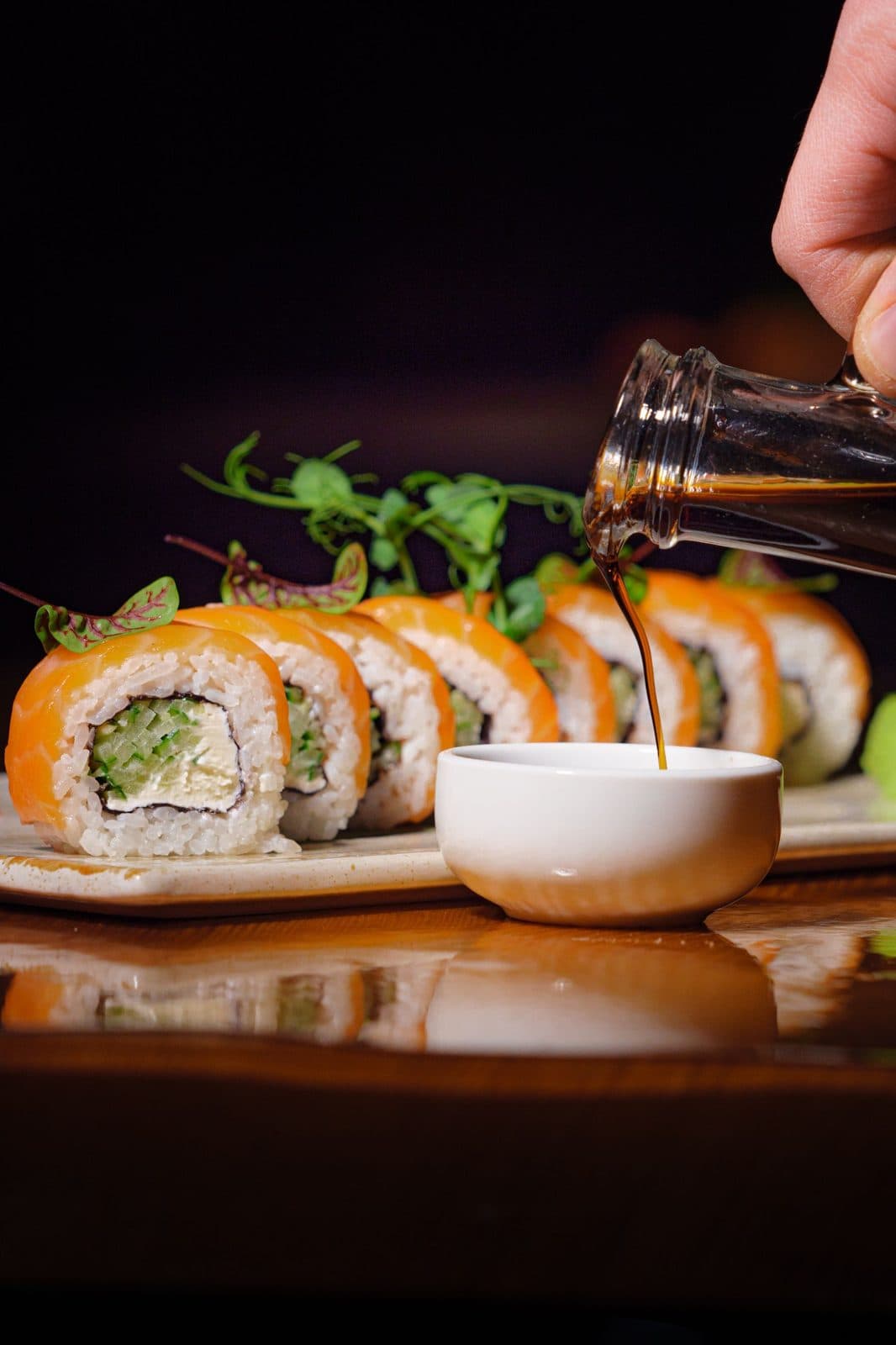 Salmon maki rolls with soy sauce being poured