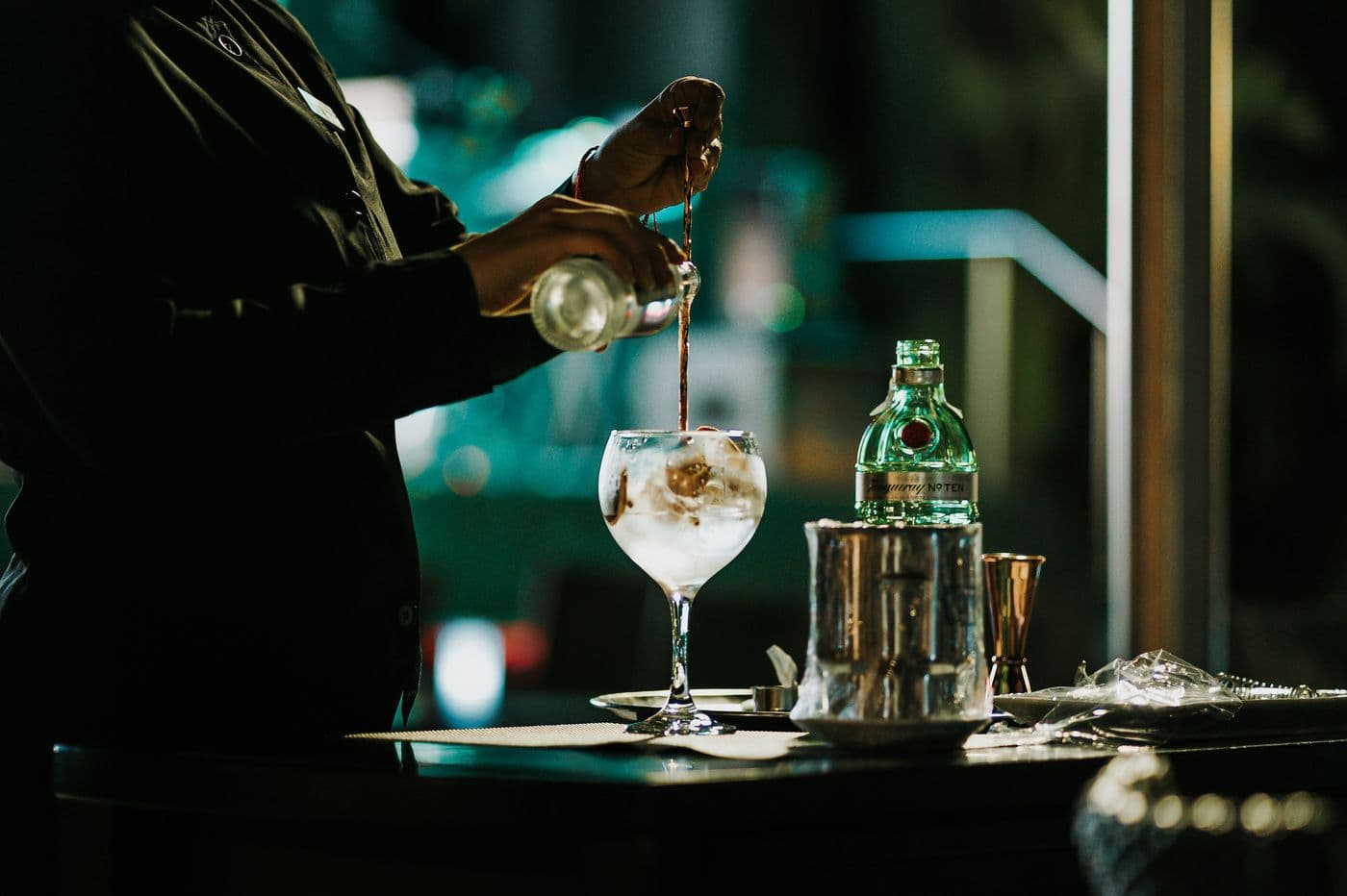 Bartender preparing a cocktail in a balloon glass in the evening