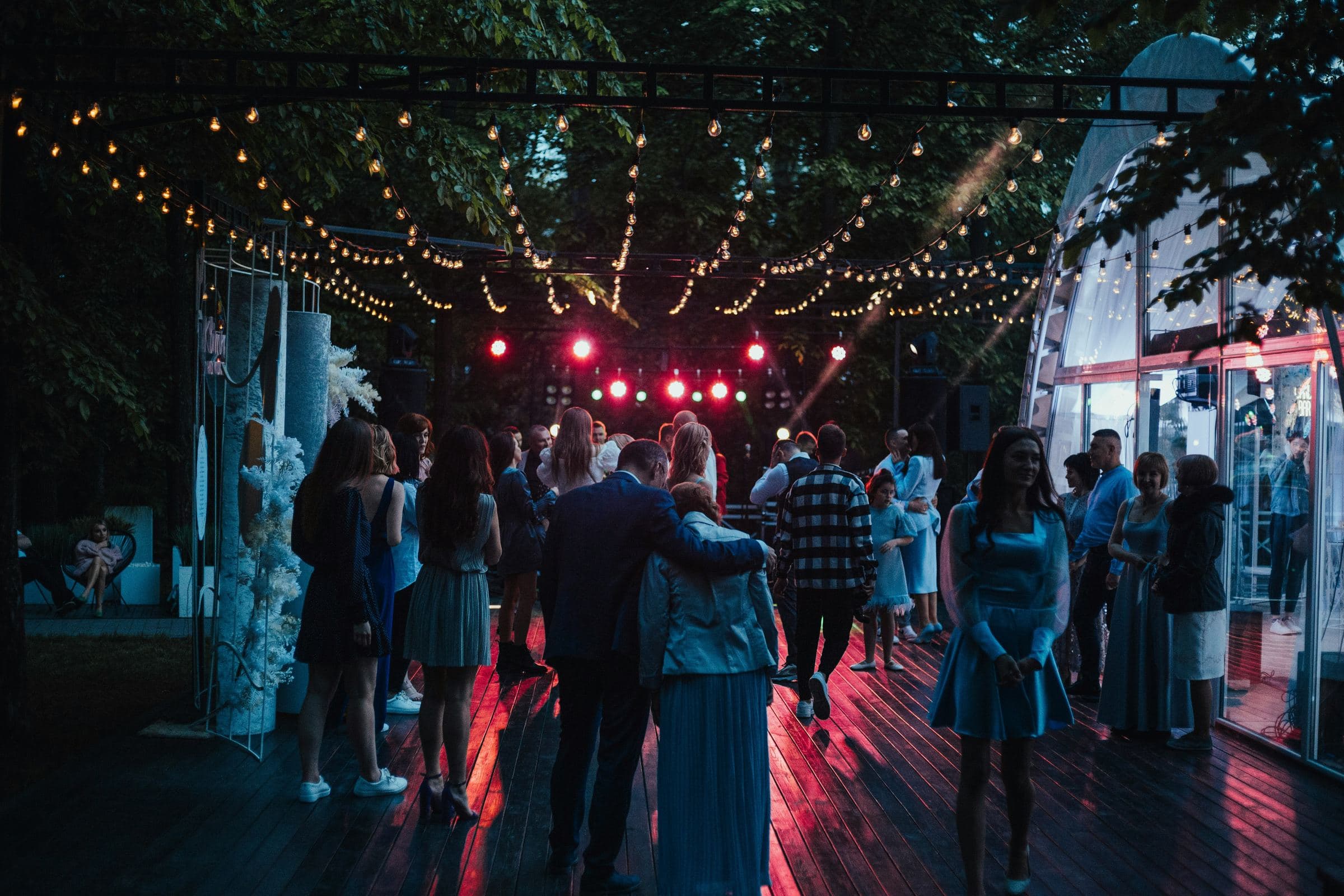 Invités sur une piste de danse en plein air, sous des guirlandes lumineuses, lors d'une soirée